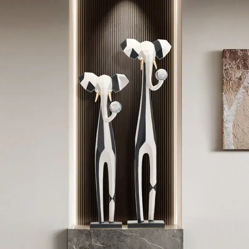 Stylized black and white elephant sculptures with gold tusks holding silver spheres for living room decorbites abstract art decor