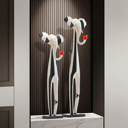 Two black and white striped elephant sculptures holding red apples in decorbites abstract art living room setup