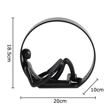 Black glossy resin figurine of abstract black characters reclining within a circular frame for aesthetic room decor