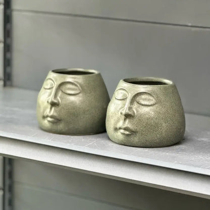 Two sage green decorbites abstract face ceramic planters with serene closed eyes for home decor accessories