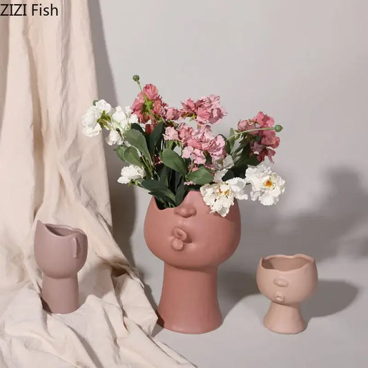 A blush pink DecorBites™ abstract face ceramic vase with puckered lips for table flowers decoration