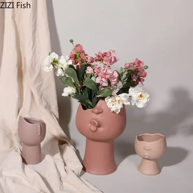 A blush pink DecorBites™ abstract face ceramic vase with puckered lips for table flowers decoration