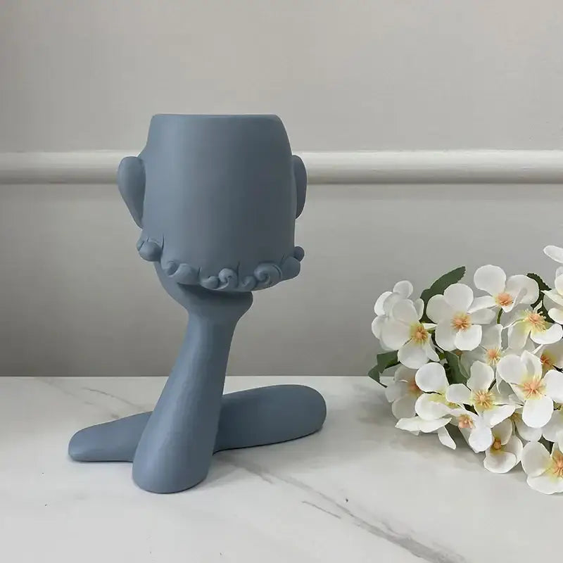 A matte gray ceramic decorbites abstract family flowerpot ornament shaped like a stylized head with ruffled details