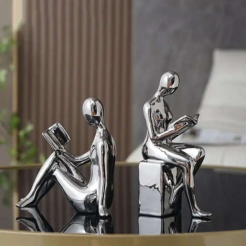 Two sleek chrome finished decorbites abstract figure bookend set depicting seated human forms reading books for stylish decor