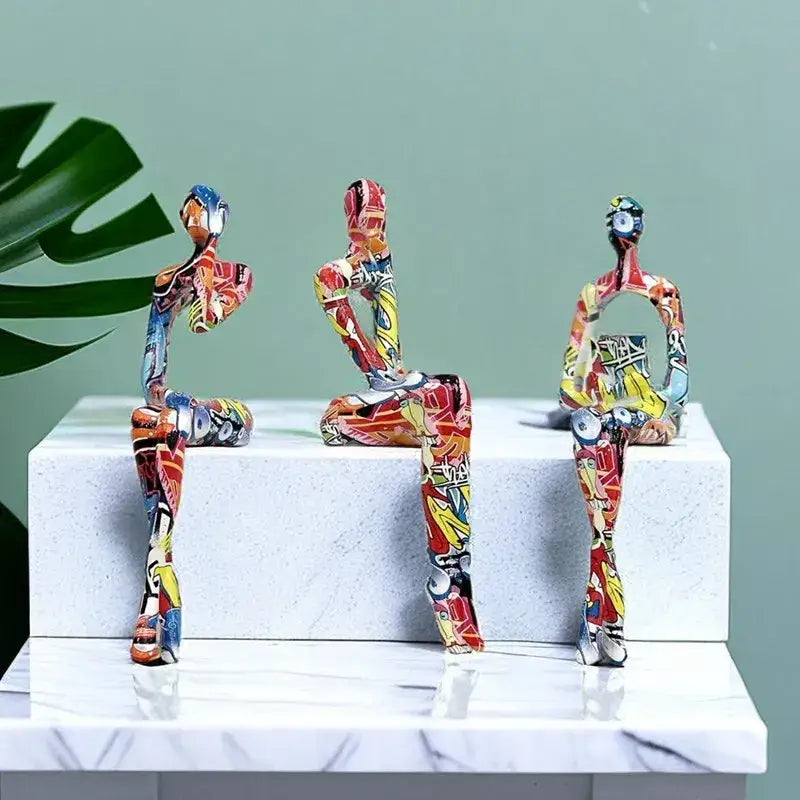 Three vibrant red yellow and blue decoBites abstract figurine modern pop art sculptures on white marble pedestal for home decor