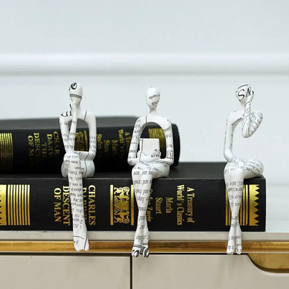 Three white paper-textured decorbites abstract figurine modern sculptures with black text seated on stacked books for home decor