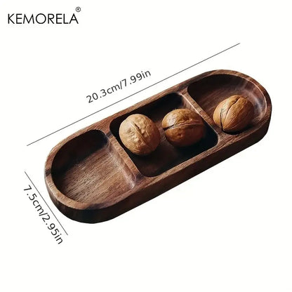Dark brown acacia wood oval dip plate with three compartments holding whole walnuts by DecorBites