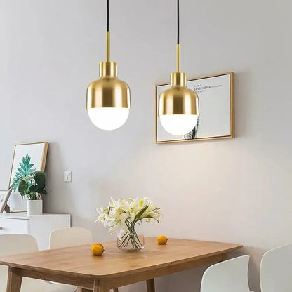Two gold-finished acrylic ball pendant lights with rounded glass shades hang above a wooden dining table decorbites pendant light