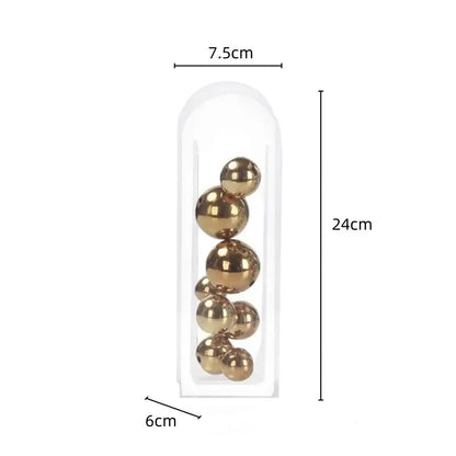 A clear plastic acrylic ball vase containing shiny gold metallic spheres in varying sizes for vase stack decor
