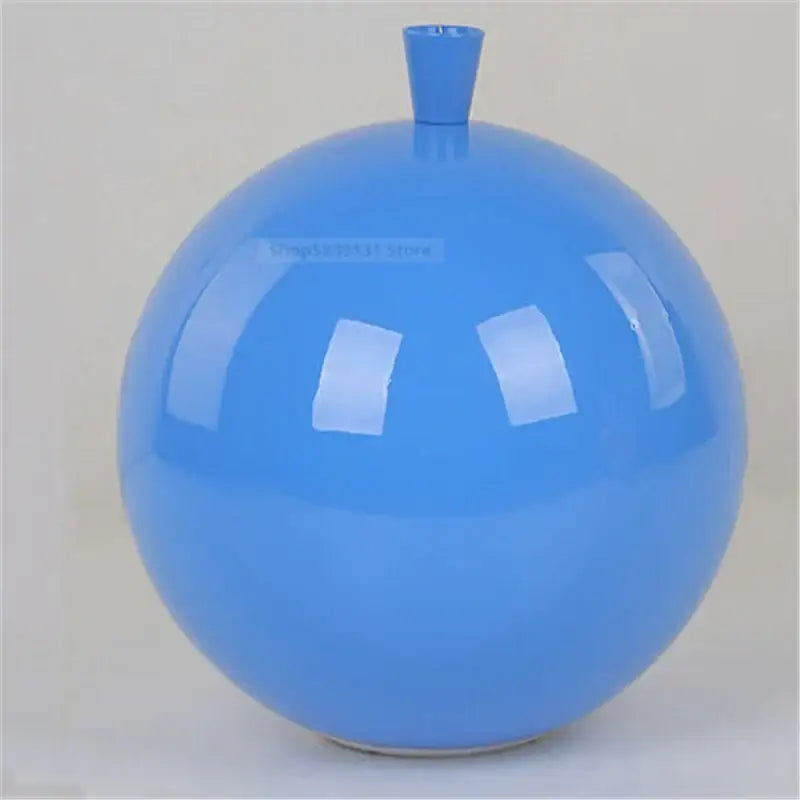 A glossy blue ceramic vase with rounded body complements modern nordic decor and acrylic balloon ceiling lights