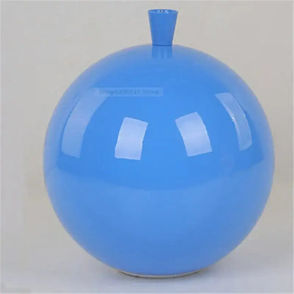A glossy blue ceramic vase with rounded body complements modern nordic decor and acrylic balloon ceiling lights