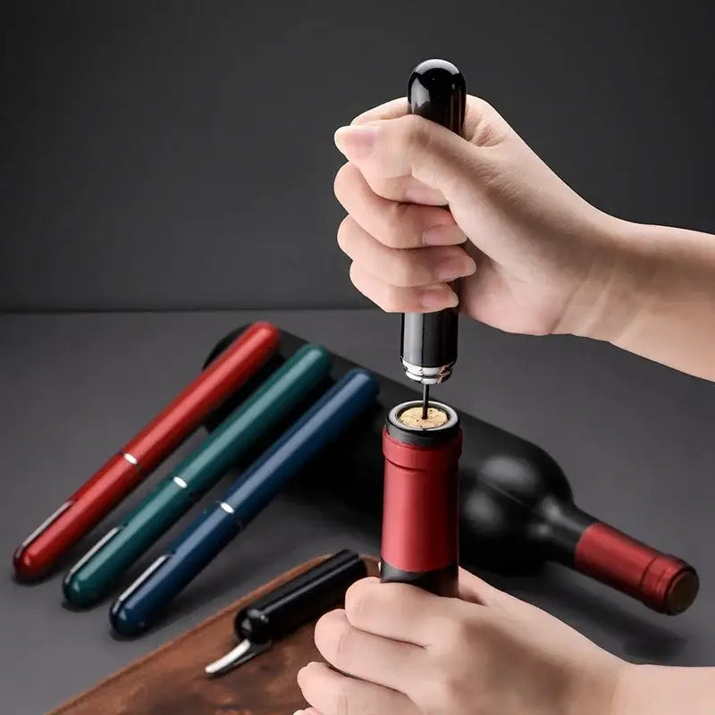 Black-handled air pump corkscrew with a metallic tip removing a cork from a red wine bottle in DecorBites™ kit