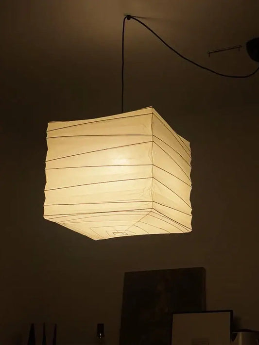 Warmly glowing DecorBites™ Akari Noguchi rice paper pendant light hanging from ceiling for bedroom or living room