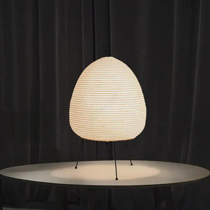 Cream-colored ribbed paper akari noguchi table lamp with sleek black metal tripod base for home and bar décor