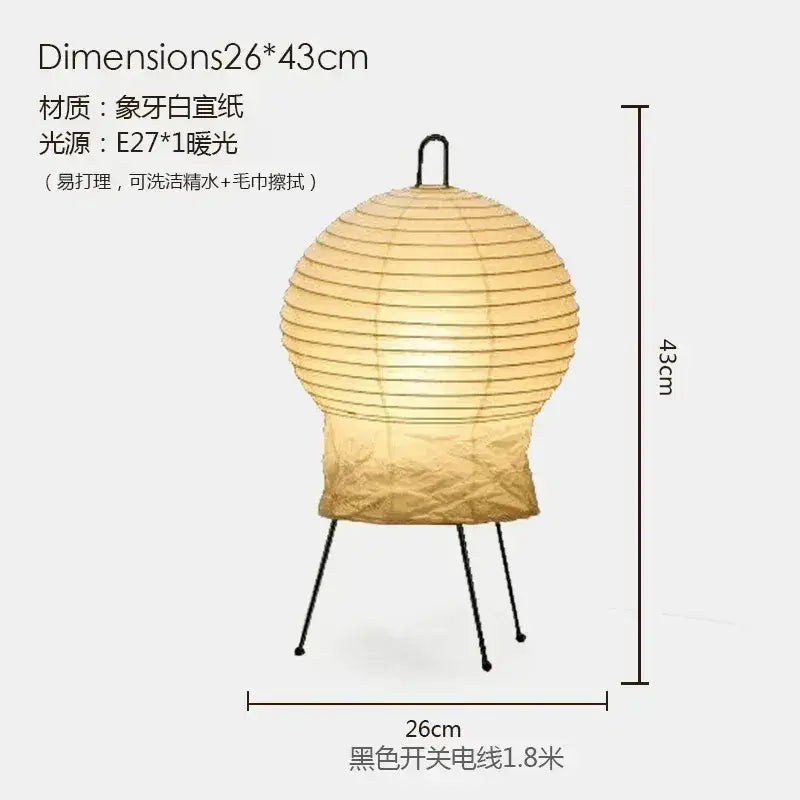 A warm glowing rice paper akari noguchi table lamp with ribbed spherical design on black metal tripod stand