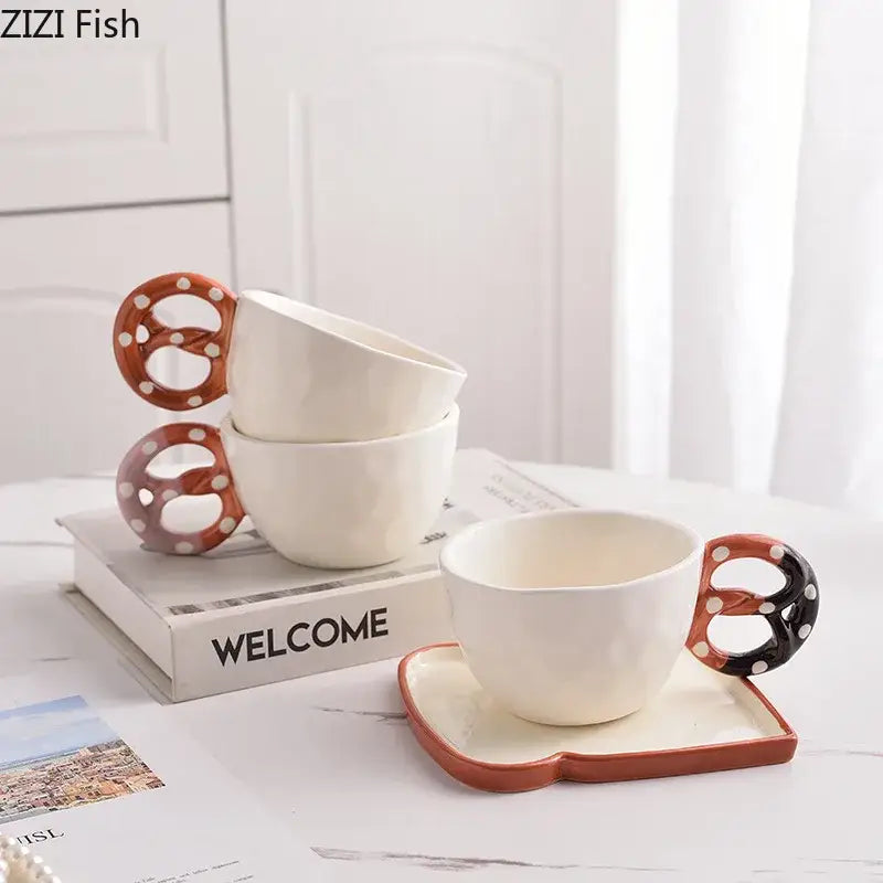White ceramic DecorBites alkali water biscuit mug with pretzel-shaped handles and polka dots on matching saucers