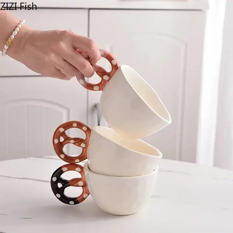 White ceramic mug set with alkali water biscuit shaped pretzel handles in brown and black with white polka dots
