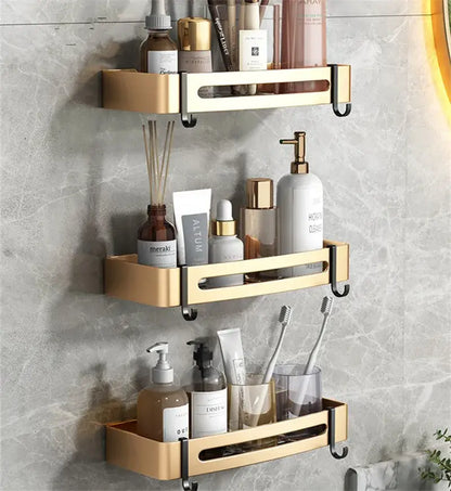 Gold-colored three-tiered aluminum bathroom corner shelf with sleek metallic finish and black hooks for wall-mounted storage