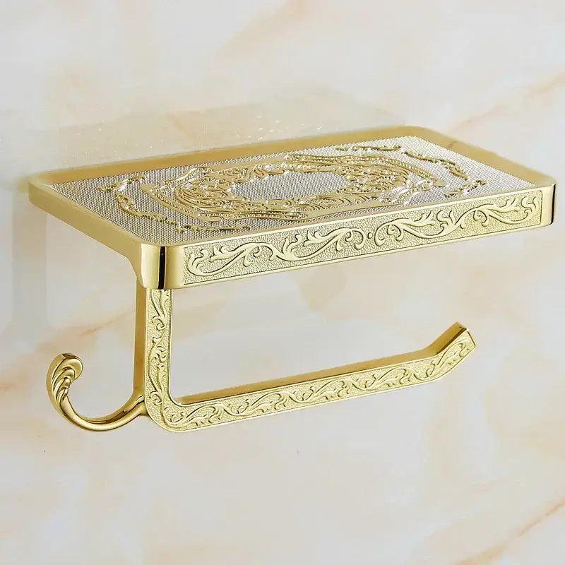 Gold-toned ornate aluminum toilet paper holder with phone rack and hook featuring floral scrollwork embossing