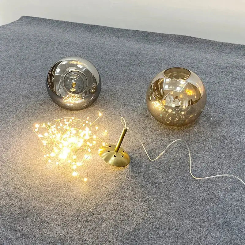 Two spherical glass globe lamps with amber glass and silver finishes on brass bases in a decorbites amber glass chandelier