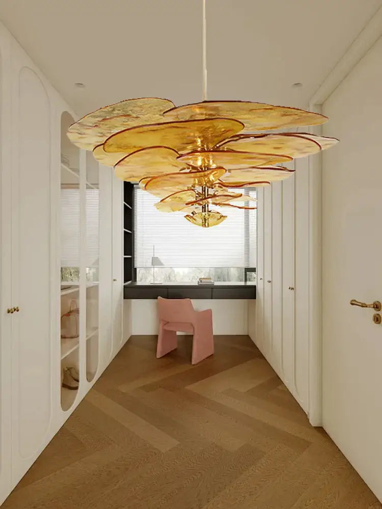 A golden amber glass chandelier with a layered floral design hanging in a luxury living space for duplex villa