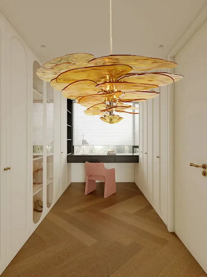 A golden amber glass chandelier with a layered floral design hanging in a luxury living space for duplex villa