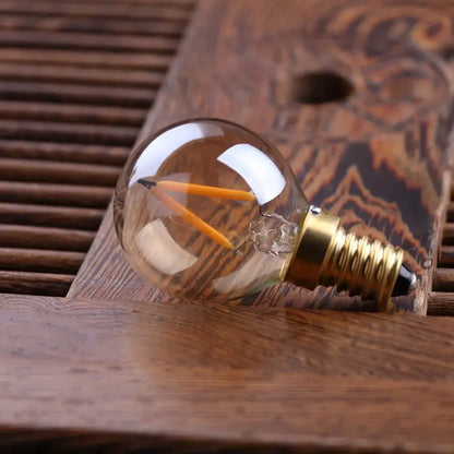 Clear glass globe bulb with two orange led filaments and brass e14 screw base for amber glass led lighting