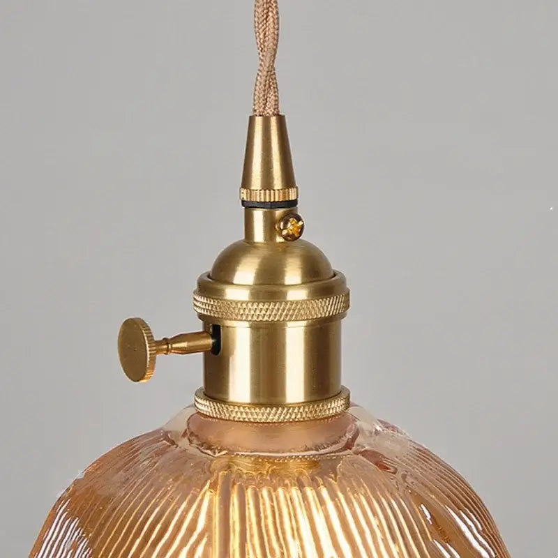 Brass-finished pendant light with ribbed amber glass led shade in a modern copper hanging fixture by DecorBites