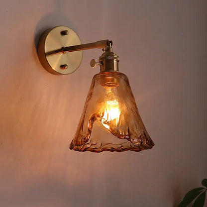 A warm amber glass led wall lamp by DecorBites with a textured hand-blown glass shade and brass sconce for living rooms