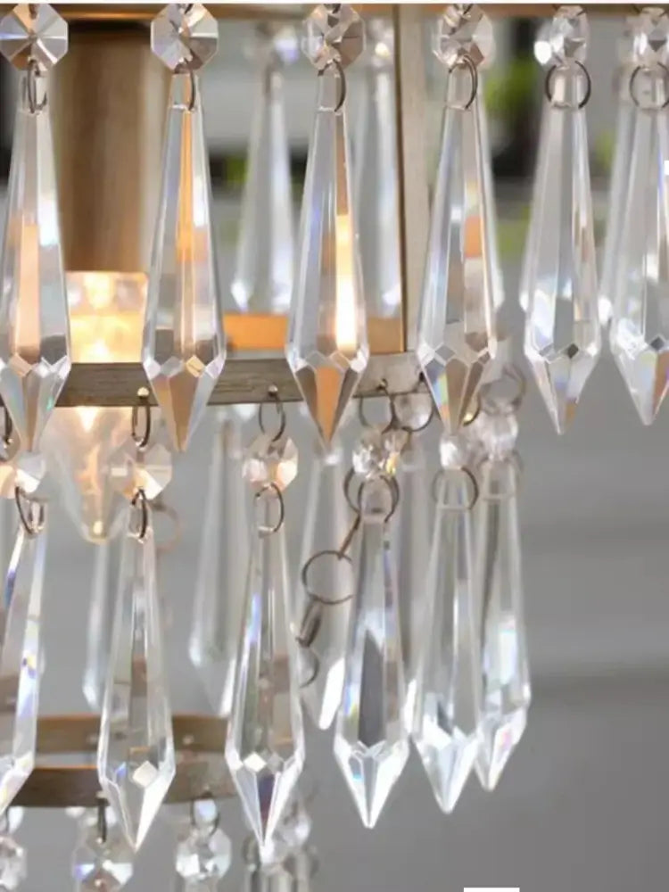 Clear crystal teardrop pendants hanging from a metallic frame on a decorbites american country antique brass chandelier