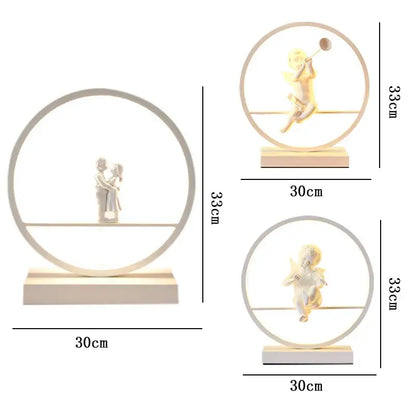 White resin angel doll bird table lamp featuring a couple kissing with integrated LED lighting in a circular frame