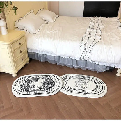 Two oval-shaped white bath rugs with black floral angel print shaggy design and ruffled edges 40x60cm decorbites