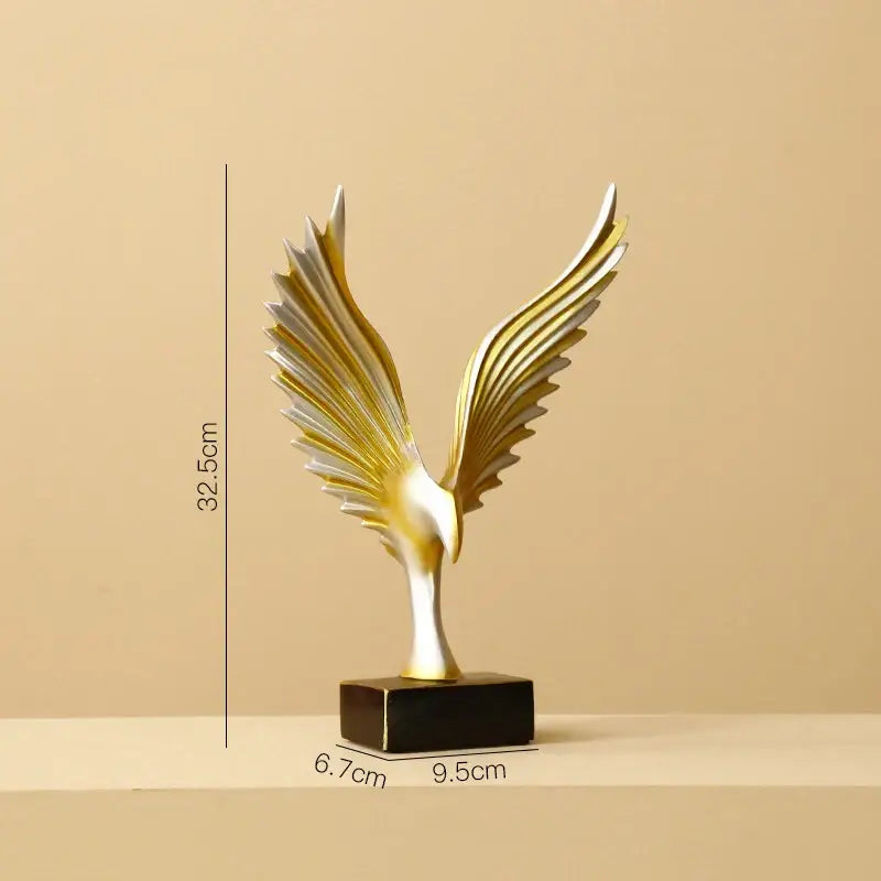 A sleek gold and silver resin angel wings sculpture with outstretched wings on a black base by decorbites