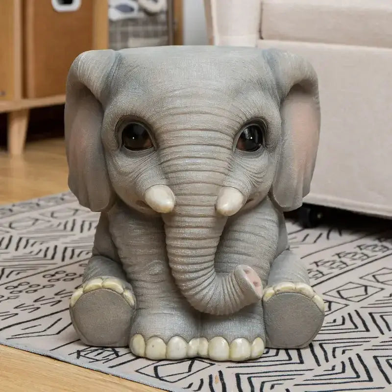 Gray resin baby elephant sculpture footstool seat with oversized ears glossy eyes and ivory tusks and feet by DecorBites