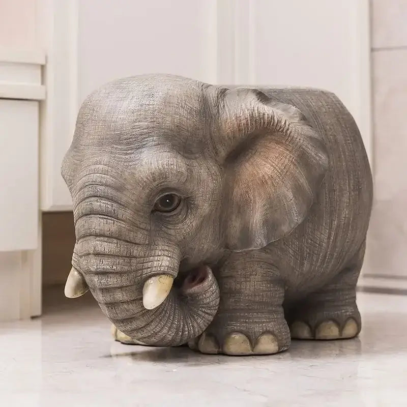 Gray elephant-shaped resin sculpture footstool seat with textured skin and white tusks for decorative seating