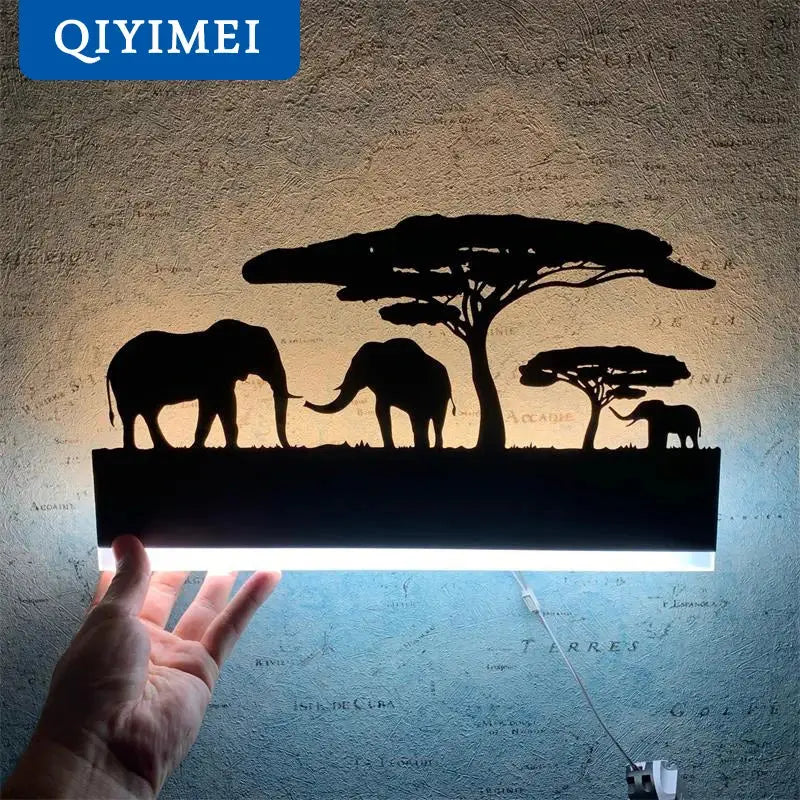 Black metal animal wall lamp featuring elephant silhouettes and acacia trees with a glowing led strip base by DecorBites™