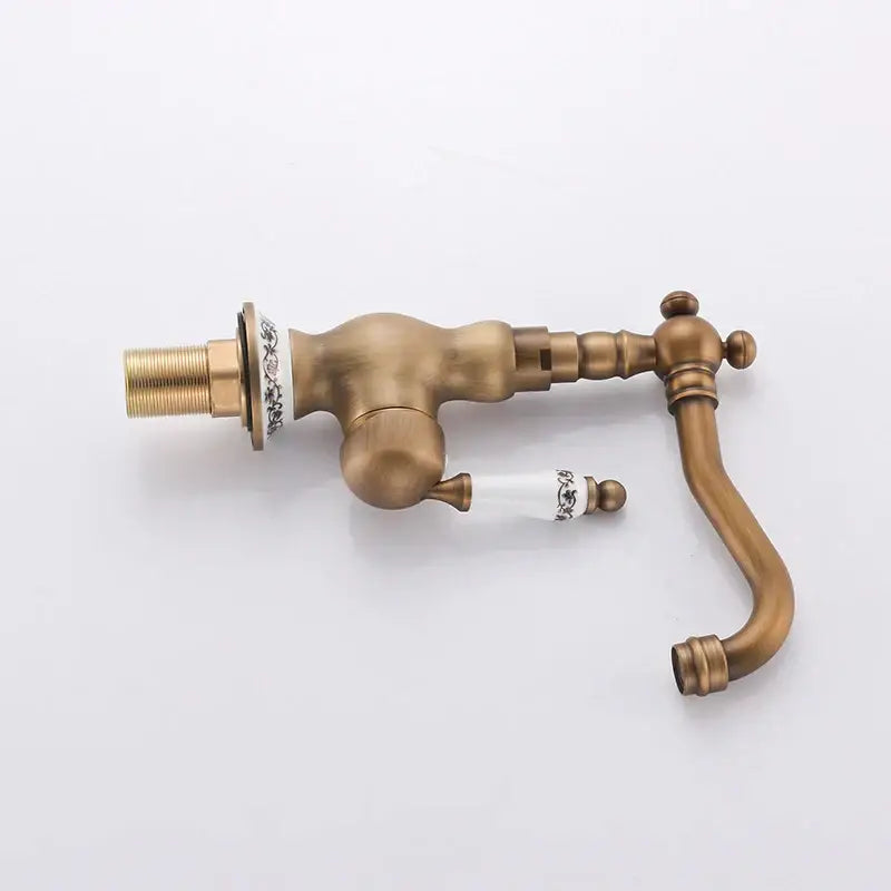 DecorBites antique brass bathroom sink faucet with ornate detailing and white ceramic handles with black floral patterns