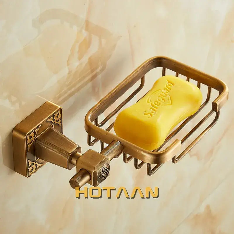 Brass-colored metal soap dish holder with ornate wall mount and wire mesh design holding yellow safeguard soap bar