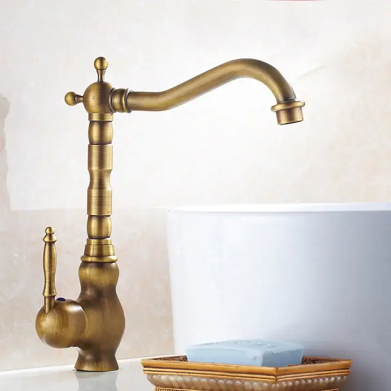 DecorBites™ antique brass ceramic handle basin faucet deck mounted with ornate detailing and curved spout