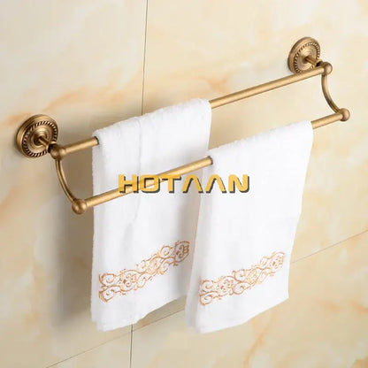 DecorBites™ antique brass double towel bar rack with ornate circular mounts holding two white towels with gold embroidery