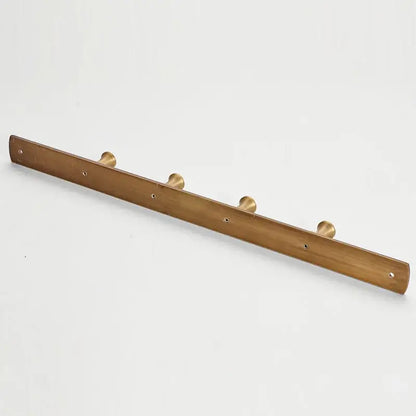 A sleek minimalist brass robe hook with antique brass finish and smooth wooden base featuring five circular hooks