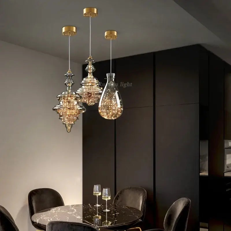 Three elegant antique brass glass chandelier pendant lights with crystal shades hanging above a dining table
