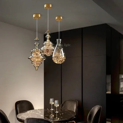 Three elegant antique brass glass chandelier pendant lights with crystal shades hanging above a dining table