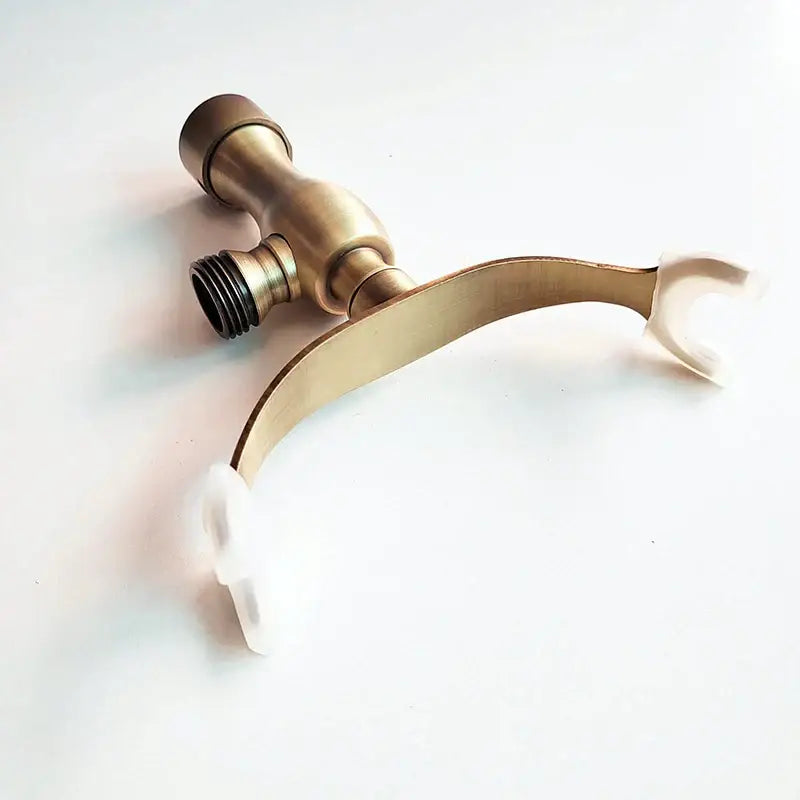 Brass-finished bathroom faucet with curved spout and white handles shown with decorbites antique brass hand shower holder bracket for wall mount
