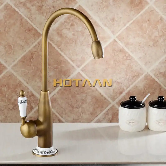 DecorBites™ antique brass kitchen faucet with curved spout and white ceramic handle featuring black floral detailing