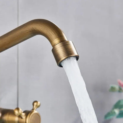 DecorBites™ antique brass kitchen faucet with swivel spout and dual handle mixer flowing water in brass finish