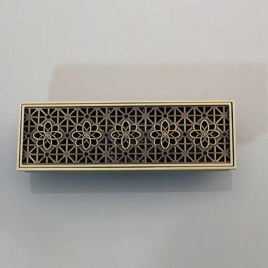Bronze-colored antique brass floor drain strainer with intricate floral cutout and brushed finish for deodorization