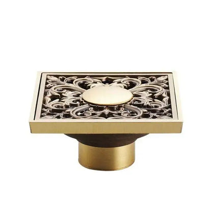 Brass-finished rectangular antique brass shower floor drain with intricate floral cutout and circular medallion design