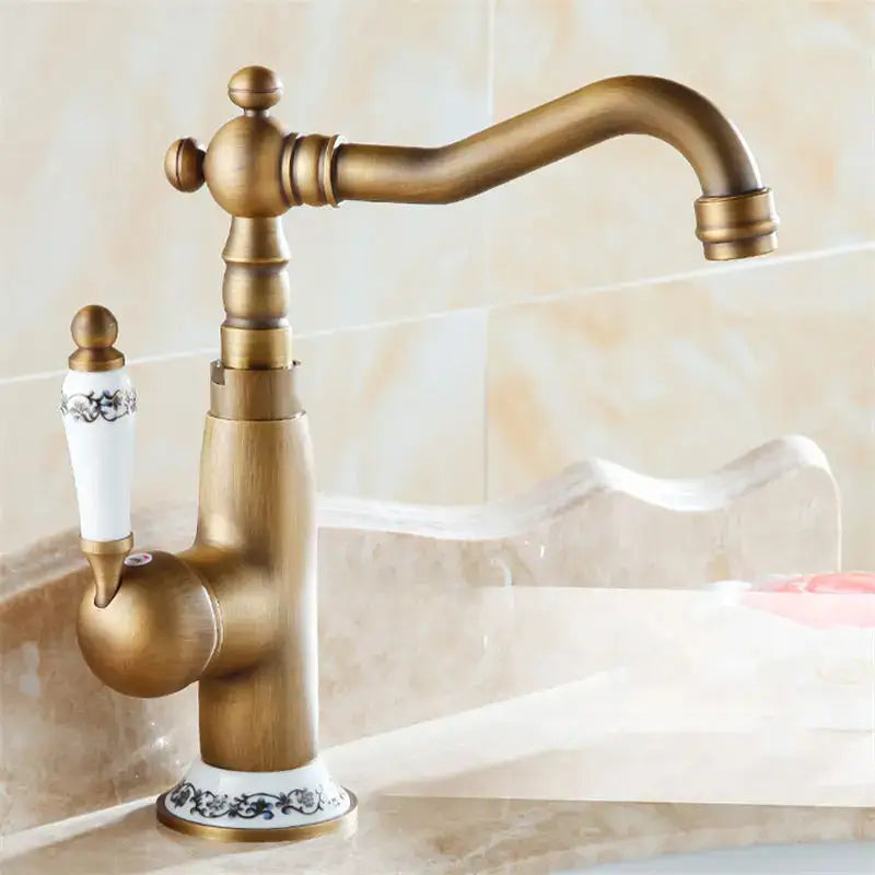 DecorBites™ antique brass single handle basin faucet with curved spout and ornate ceramic handle with black floral detailing