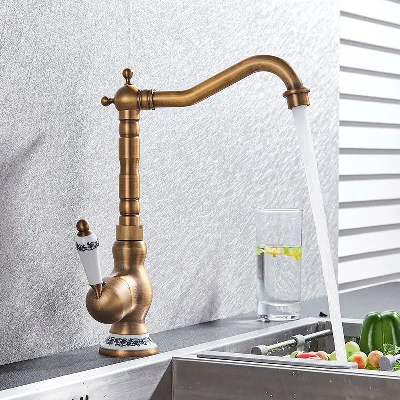 Decorbites antique brass kitchen sink faucet with white ceramic handle and black ornate detailing for hot and cold water mixing